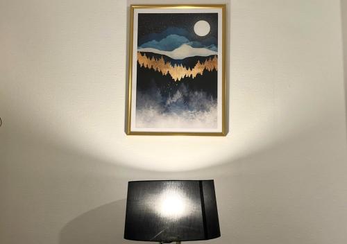 a picture hanging on a wall above a lamp at Le Charme D'Antan - Terrasse - Balcon - Hypercentre Evreux in Évreux