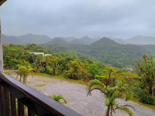 a balcony with a view of mountains and palm trees at 美ら海　みるきぃうえぃ in Motobu