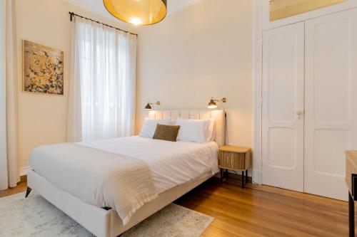 a white bedroom with a white bed and a window at Canto do Atlantico - City Centre in Ponta Delgada
