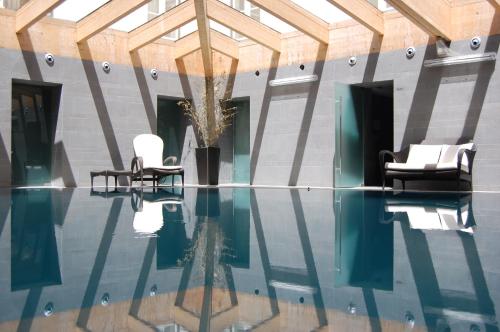 a pool with two chairs and a vase with a plant at Curia Palace Hotel & Spa in Curia