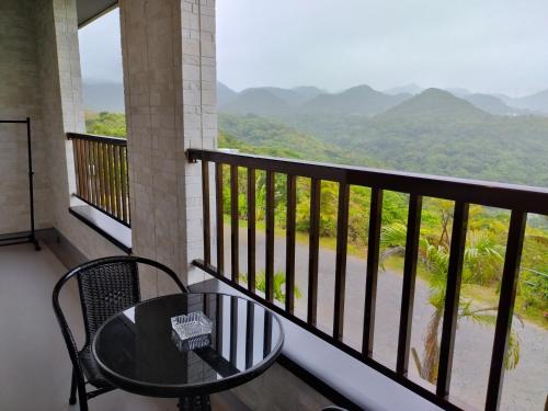 a balcony with a table and a view of mountains at 美ら海　みるきぃうえぃ in Motobu