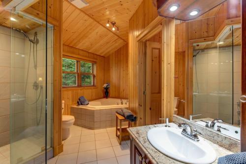y baño con bañera, lavamanos y ducha. en Fiddler Lake Resort Chalet Bear 34 en Mille-Isles