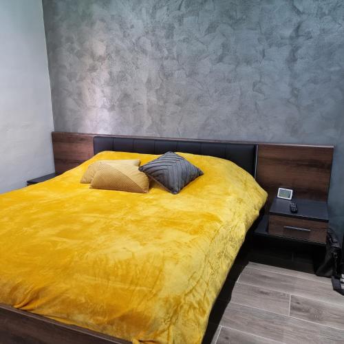Una cama amarilla con dos almohadas encima. en Luqa Premium Rooms en Luqa