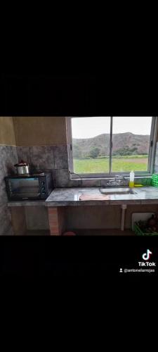 a kitchen window with a sink and a microwave at TINKUNAKAMA in Humahuaca