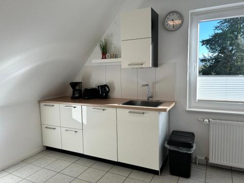 a kitchen with white cabinets and a sink and a window at Moderne Ferienwohnung in ruhiger Lage in Neetze