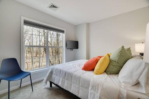 um quarto com uma cama com uma janela e uma cadeira azul em Tranquil Elegance at Your Private Creek Oasis. 30+ em East Stroudsburg