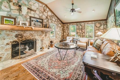 a living room with a stone wall at The Camp Blanco by Lodgewell - Riverfront retreat 2 Homes, Bunk House, Game Room & more in Blanco