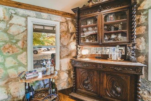 a bar in a room with a large wooden cabinet at The Camp Blanco by Lodgewell - Riverfront retreat 2 Homes, Bunk House, Game Room & more in Blanco