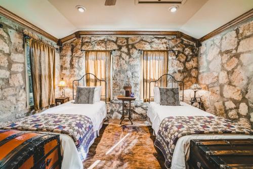 two beds in a room with stone walls at The Camp Blanco by Lodgewell - Riverfront retreat 2 Homes, Bunk House, Game Room & more in Blanco