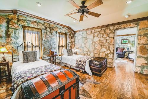a bedroom with two beds and a ceiling fan at The Camp Blanco by Lodgewell - Riverfront retreat 2 Homes, Bunk House, Game Room & more in Blanco
