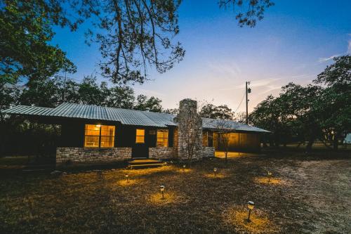 a small stone house with a metal roof at The Camp Blanco by Lodgewell - Riverfront retreat 2 Homes, Bunk House, Game Room & more in Blanco