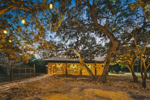 a house with lights hanging from a tree at The Camp Blanco by Lodgewell - Riverfront retreat 2 Homes, Bunk House, Game Room & more in Blanco