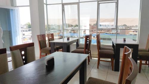 una sala da pranzo con tavoli, sedie e finestre di Samaná a Tacna