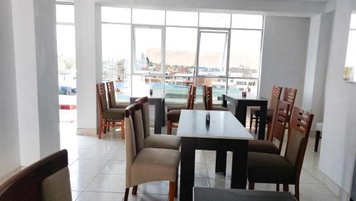 a dining room with a table and chairs and a large window at Samaná Hostal in Tacna