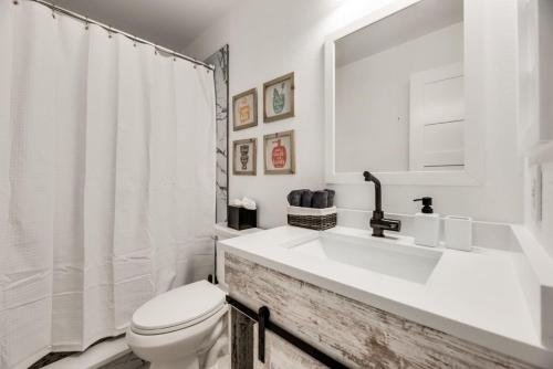 a white bathroom with a sink and a toilet at Little elm 5BR Gem Pool Spa Firepit Game Room in Little Elm