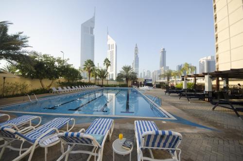 a swimming pool with chairs and a table in front of a building at The Apartments, Dubai World Trade Centre in Dubai