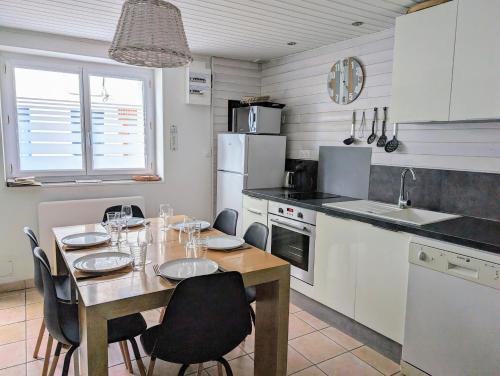 une cuisine avec une table avec des chaises et une salle à manger dans l'établissement Agréable maison rénovée en hyper centre avec patio, à Pornic