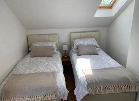 two beds in a small room with a window at Trelowen Cottage in Callington