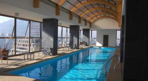 a large swimming pool in a building with windows at AMISTAR BELLAS ARTES in Santiago