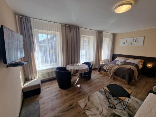 1 dormitorio con 1 cama, 1 mesa y 2 ventanas en ApartHouse Apartamenty Centrum, en Katowice