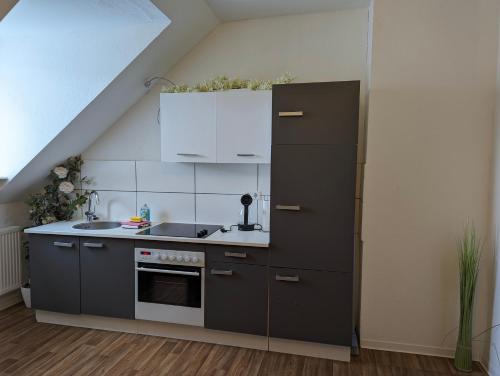 eine Küche mit weißen Schränken und einem schwarzen Kühlschrank in der Unterkunft Cityhouse - Wiesen in Wuppertal