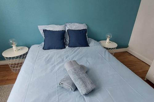 - un lit avec 2 oreillers bleus et des serviettes dans l'établissement Pin Pon d'Or, petite maison proche de la plage, à Andernos-les-Bains