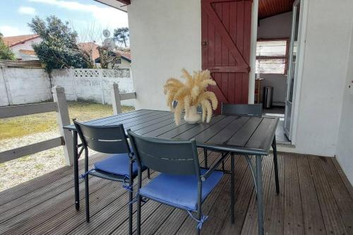 une table en bois avec quatre chaises sur une terrasse dans l'établissement Pin Pon d'Or, petite maison proche de la plage, à Andernos-les-Bains