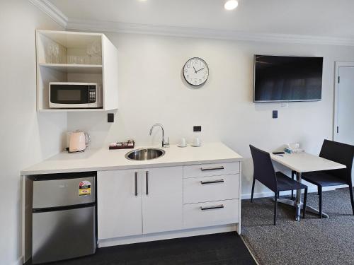 a kitchen with a sink and a microwave and a table at Superior Dunedin Apartments in Dunedin
