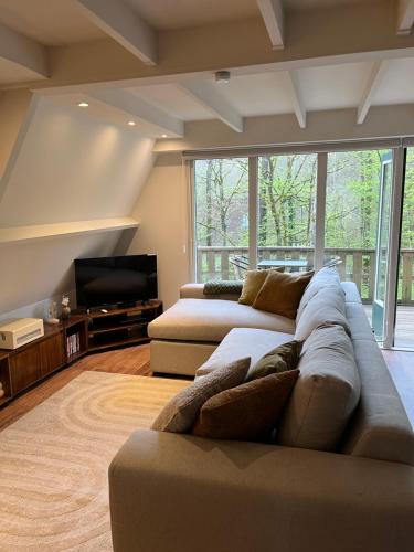 Una sala de estar con un sofá y un televisor de pantalla plana. en De Lodge, en Durbuy