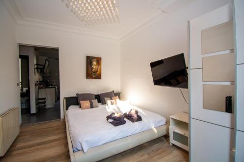 Cette chambre comprend un lit avec des draps blancs et une télévision. dans l'établissement Cosy 1 BDR Kremlin-Bicêtre (2 min Porte d'Italie), au Kremlin-Bicêtre