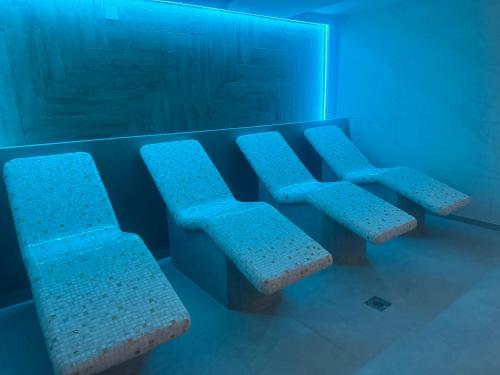 three chairs in a waiting room with blue lighting at Apartmani K&V in Veliko Gradište