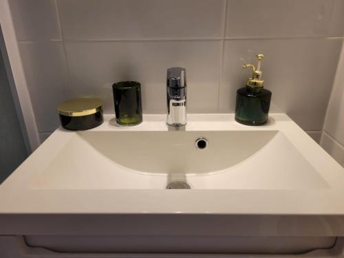 a white bathroom sink with three bottles and jars at Le raffiné - Studio avec balcon, proche de l'océan in La Baule