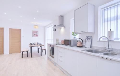a white kitchen with a sink and a table at Shaw Heath Cottage - Charming Holiday Home In the Heart of Stockport - Free Parking in Stockport