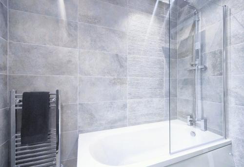 a bathroom with a shower and a bath tub at Shaw Heath Cottage - Charming Holiday Home In the Heart of Stockport in Stockport