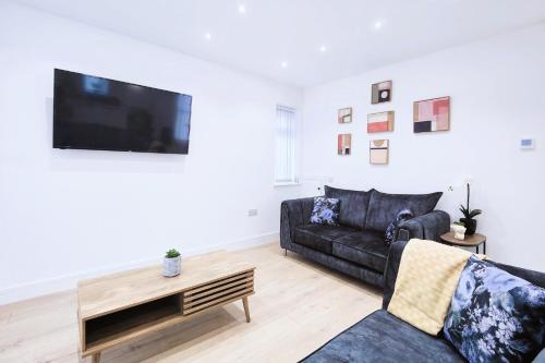 a living room with a black couch and a flat screen tv at Shaw Heath Cottage - Charming Holiday Home In the Heart of Stockport - Free Parking in Stockport