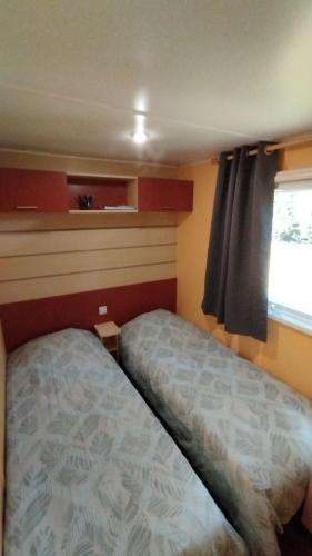 Habitación pequeña con cama y ventana en Charmant Mobil Home 6 personnes avec clim réversible en Boofzheim
