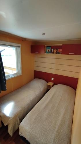 2 camas en una habitación pequeña con ventana en Charmant Mobil Home 6 personnes avec clim réversible en Boofzheim