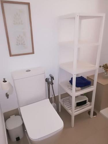 a white room with a toilet and a shelf at 1 linea playa Islantilla in Islantilla