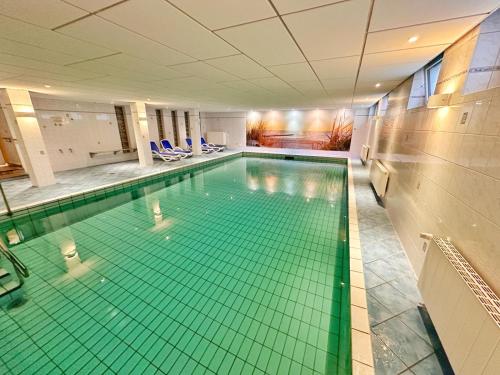 uma piscina interior com azulejos verdes no chão em Watt & Wind - Tolles Schwimmbad em Cuxhaven