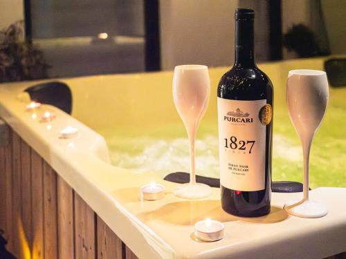 a bottle of wine and two glasses on a bath tub at GAVAS Jacuzzi Relax Zen in Cluj-Napoca