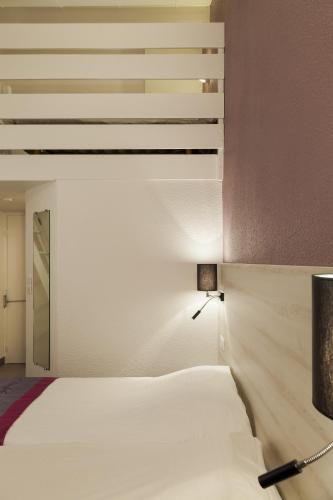 a bedroom with a white bed and a lamp at Kyriad Lille Est - Villeneuve d'Ascq in Villeneuve d'Ascq