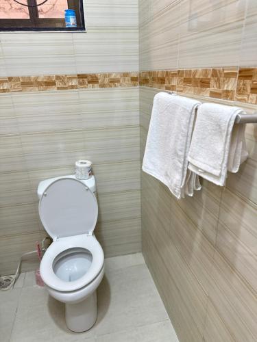 a bathroom with a toilet and towels on a wall at Rejao Homes in Dar es Salaam