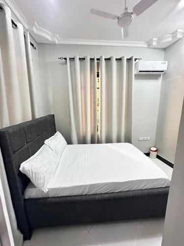 1 dormitorio con 1 cama con sábanas y cortinas blancas en Rejao Homes en Dar es Salaam