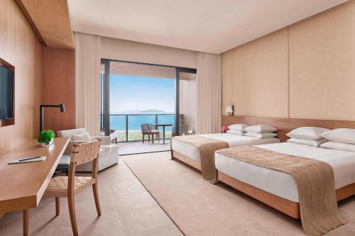 a hotel room with two beds and a view of the ocean at The Sanya EDITION in Sanya