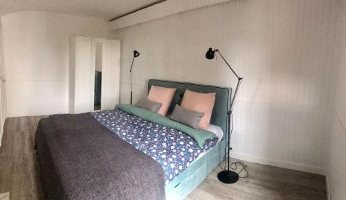 Schlafzimmer mit einem Bett mit rosa und grünen Kissen in der Unterkunft Maison situé au centre d'Enghien les Bains avec jardin et parking privé in Enghien-les-Bains