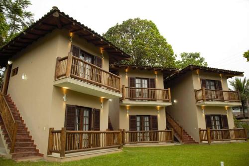 a large house with wooden balconies and a yard at Vila dos Caetés - Suíte 04 - Barra do Sahy in Barra do Sahy