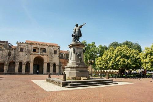 a statue in the middle of a courtyard with a building at J. B Apartamentos in Santo Domingo