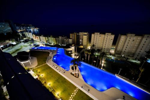 a large swimming pool in a city at night at Benidorm Sunset Cliffs in Benidorm