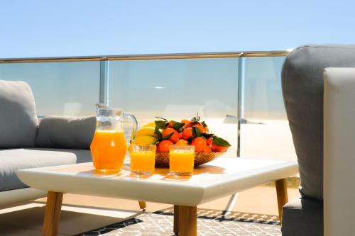 a table with two glasses of orange juice and a bowl of fruit at Benidorm Sunset Cliffs in Benidorm