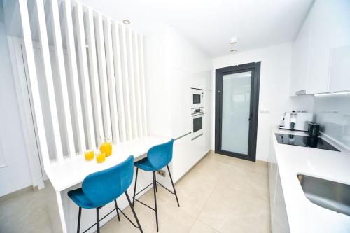 a kitchen with a white table and blue chairs at Benidorm Sunset Cliffs in Benidorm